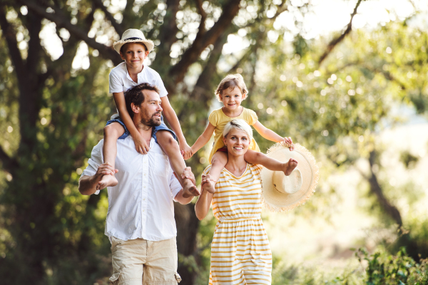 Happy young family with small children spending time together outside in green summer nature.