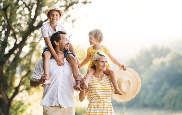 Happy young family with small children spending time together outside in green summer nature.