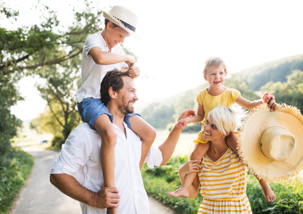 Happy young family with small children spending time together outside in green summer nature.