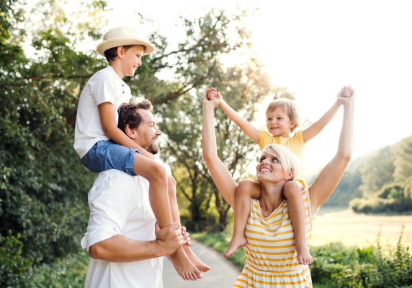 Happy young family with small children spending time together outside in green summer nature.