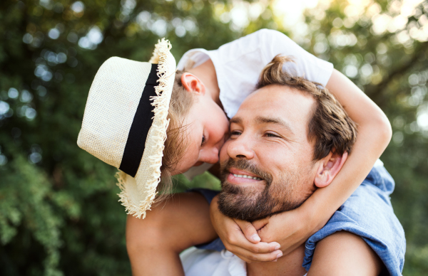 Young father in nature giving a small son a piggyback ride. A close-up.