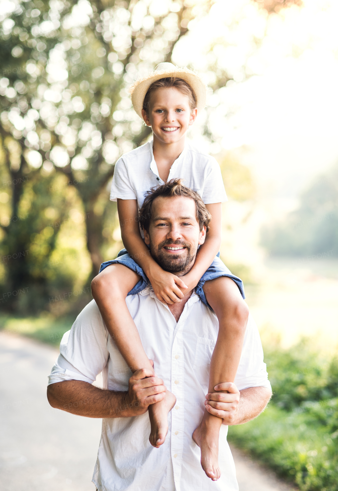 Young father in nature giving a small son a piggyback ride.