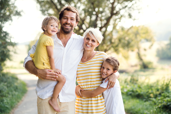 A portrait of happy young family with small children spending time together outside in green summer nature.