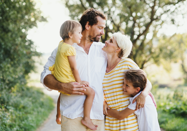 A portrait of happy young family with small children spending time together outside in green summer nature.