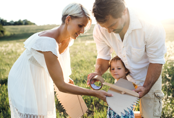 A young family with small daughter playing on a meadow in nature.