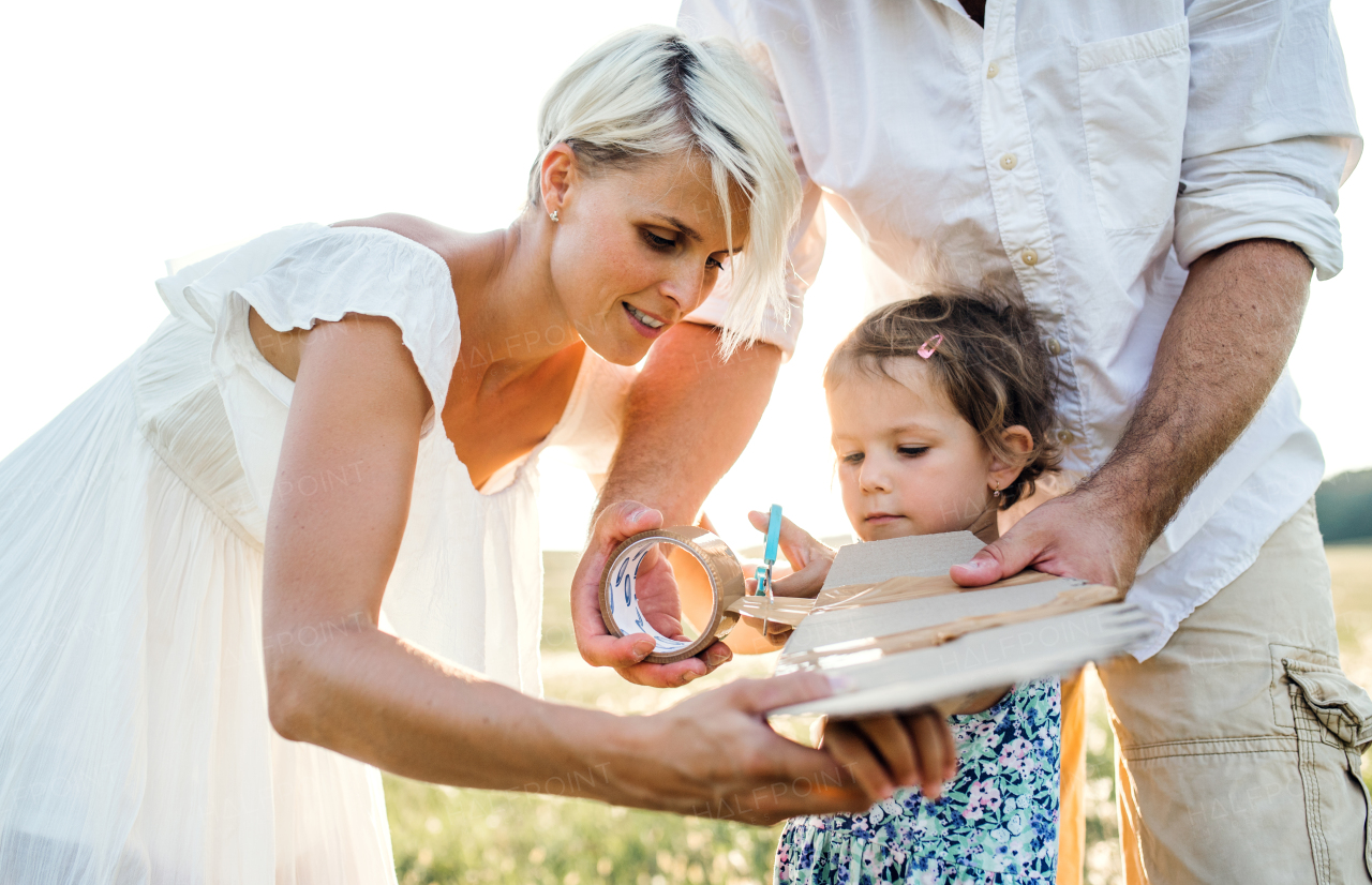 A young family with small daughter playing on a meadow in nature.