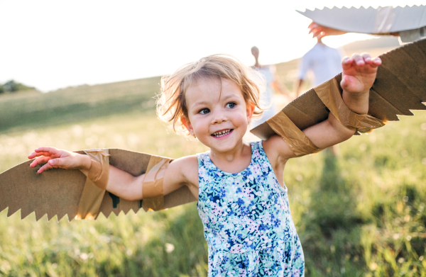 A cute small girl playing on a meadow in nature, flying with wings.