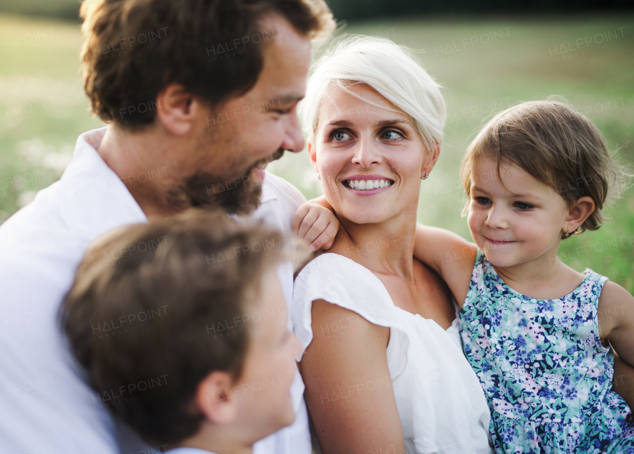 Happy young family with small children spending time together outside in green summer nature at sunset.