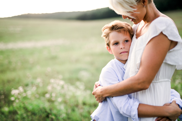 A small boy hugging his young mother outdoors in nature. A copy space.