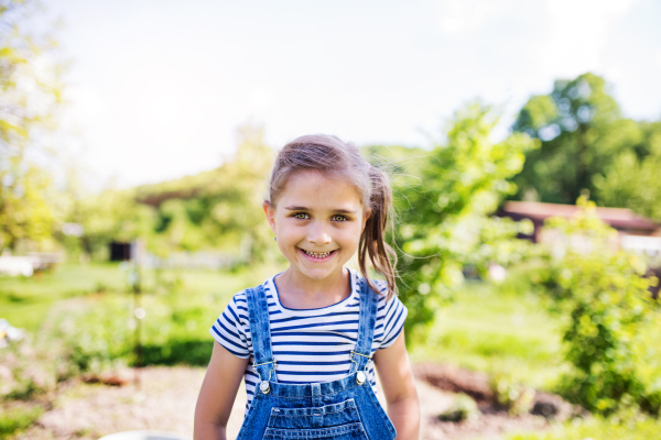 A portrait of a small happy girl in the garden in spring nature.