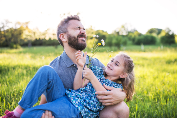 Father with a small daughter having fun in sunny spring nature.