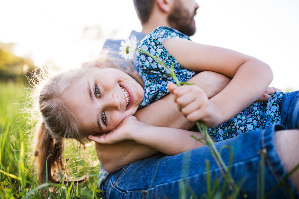 Unrecognizable father with a small daughter having fun in sunny spring nature.