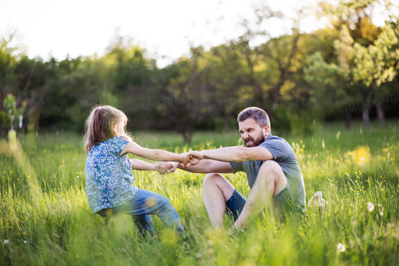 Father with a small daughter having fun in sunny spring nature.