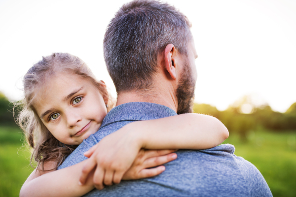 Unrecognizable father with a small daughter having fun in sunny spring nature.