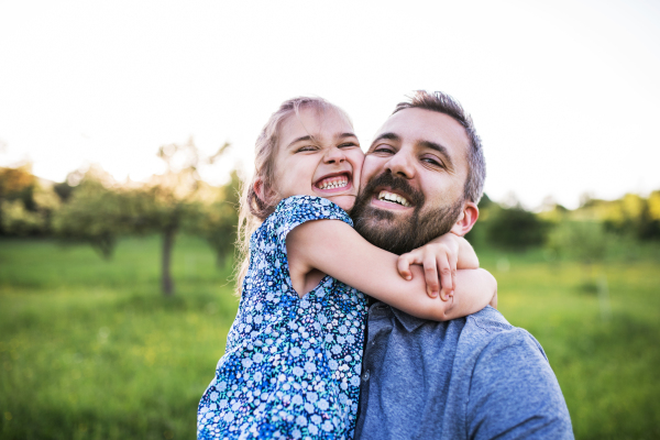 Father with a small daughter having fun in sunny spring nature, taking selfie.