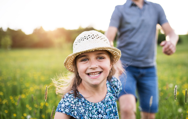 Unrecognizable father with a small daughter running in spring nature.