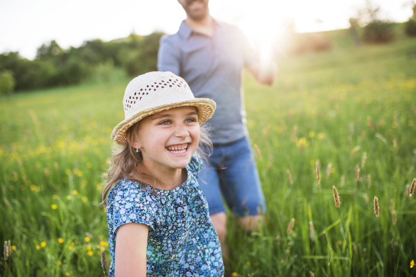 Unrecognizable father with a small daughter running in spring nature.