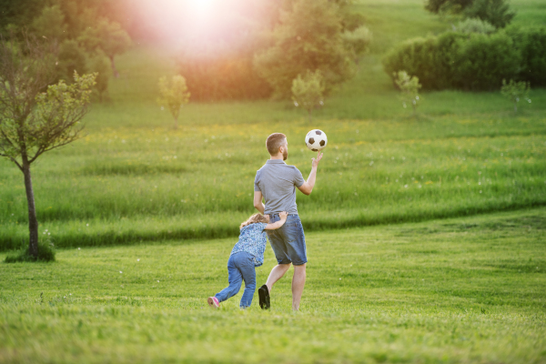 Father with a small daughter playing with a ball in sunny spring nature.