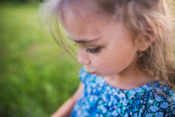 A portrait of a small girl in the garden in spring nature. Copy space. Close up.