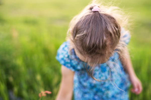 An unrecognizable small girl in the garden in spring nature. Close up.