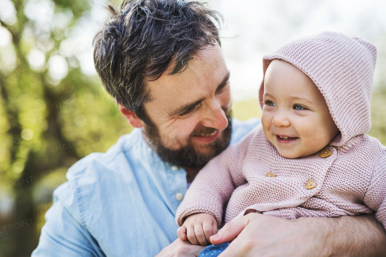 A father with his toddler daughter outside in green sunny spring nature.