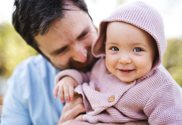 A father with his toddler daughter outside in green sunny spring nature.