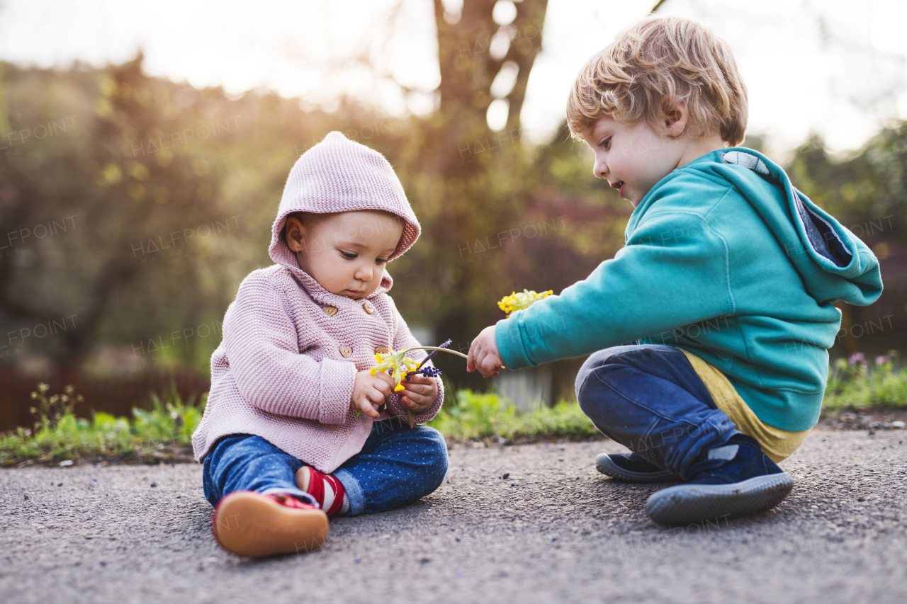 An unrecognizable father with his two toddler children outside on a sunny spring walk.