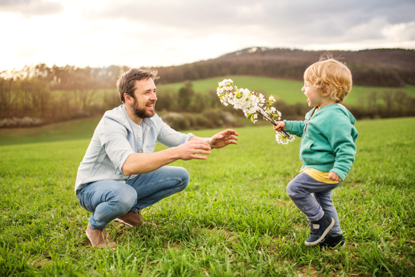 A father with his toddler son outside in green sunny spring nature.