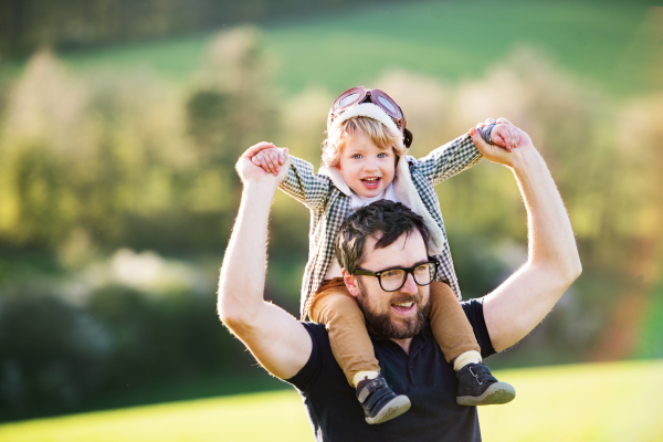 A father with his toddler son outside in green sunny spring nature, having fun.