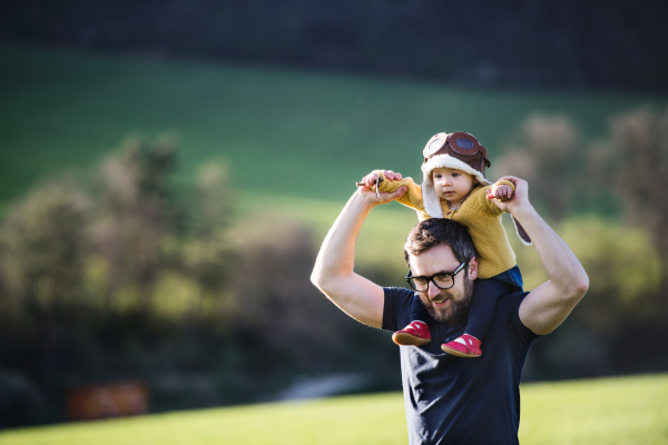 A handsome father with his toddler daughter outside in green sunny spring nature. Copy space.