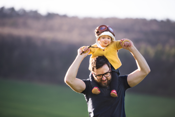 A handsome father with his toddler daughter outside in green sunny spring nature. Copy space.