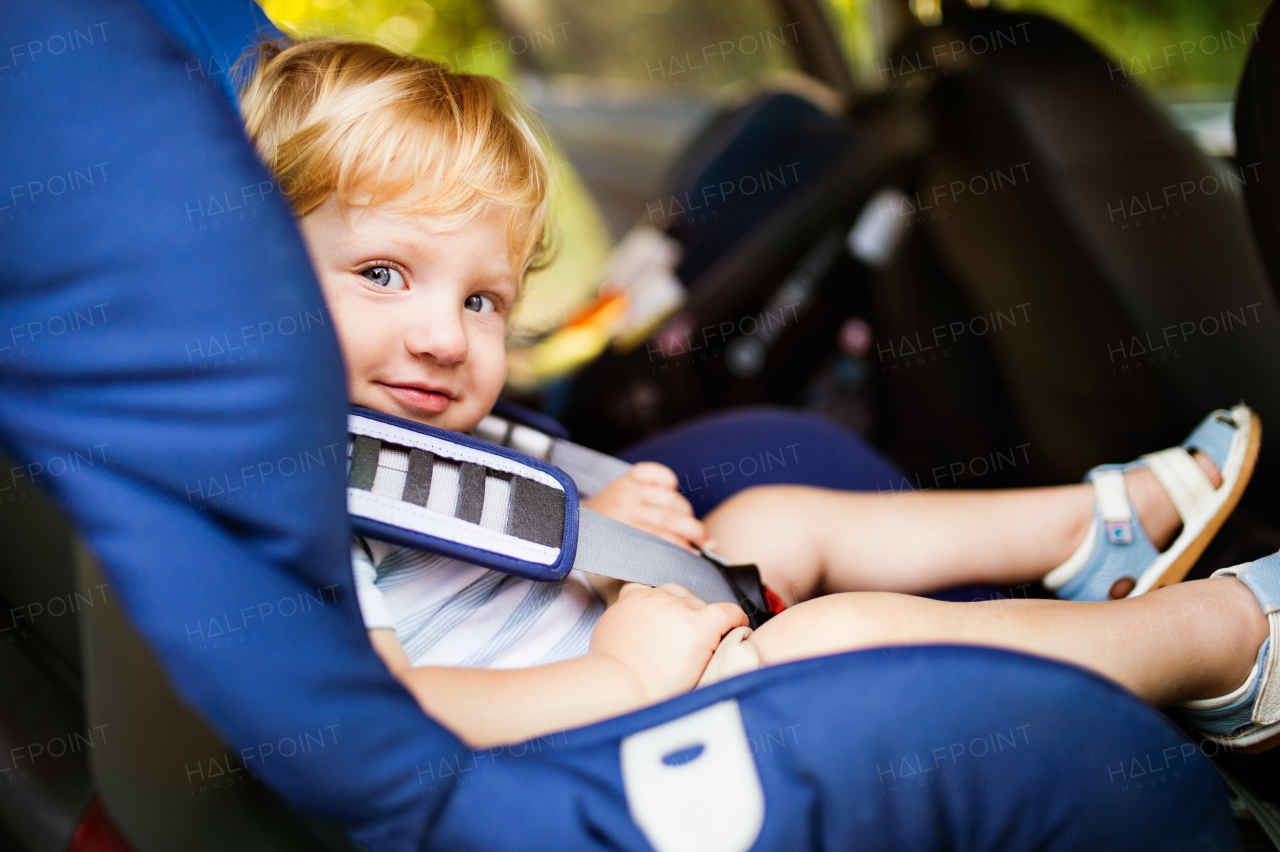 Cute little boy sitting in the car seat in the car. Summer time.