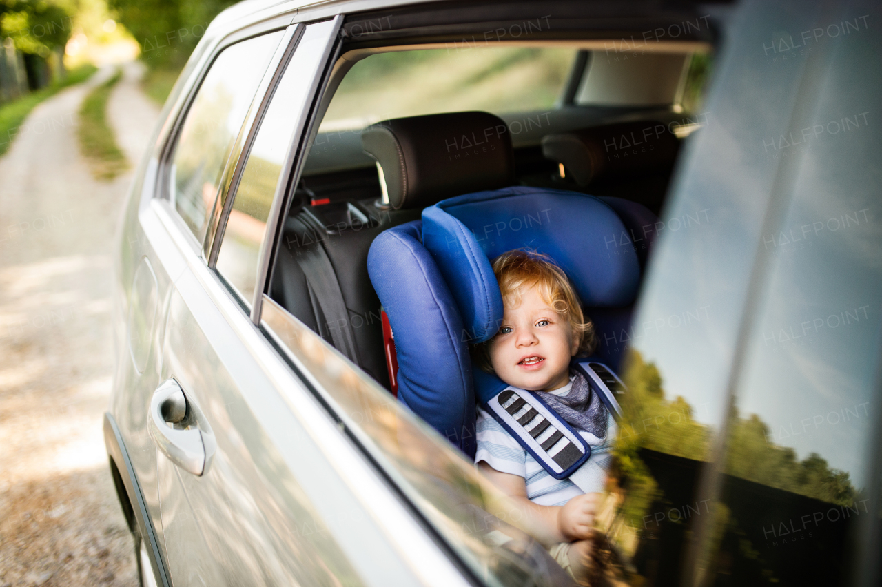 Cute little boy sitting in the car seat in the car. Summer time.