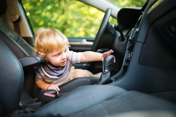 Cute little boy playing in the car, pretending to drive it.