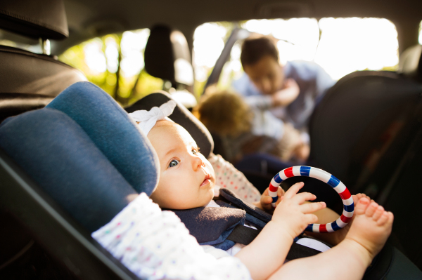 Cute little baby girl fastened with security belt in safety car seat.