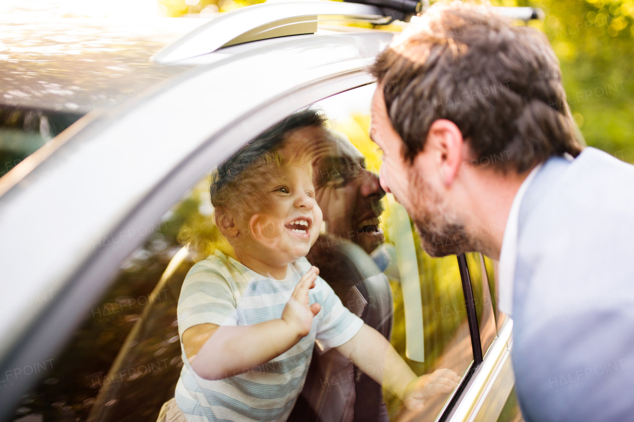 Cute little boy in the car looking at his father. Son waving at his father.