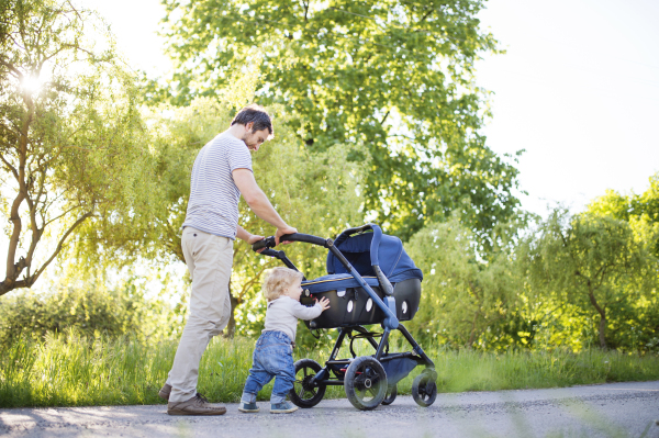 Young father with his kids ouside on walk in park.