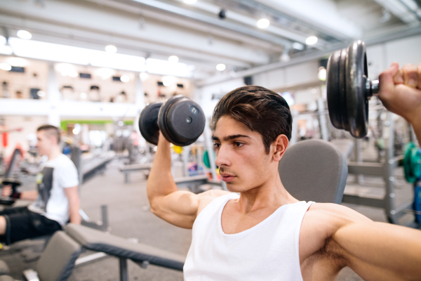 Young hispanic fitness man in gym on bench, working out with weights