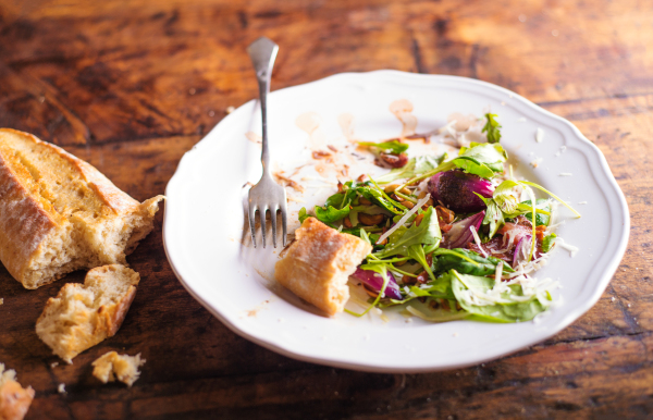 Colorful rucola salad on white porcelain plate with brusheta bread. Studio shot on old wooden table background.