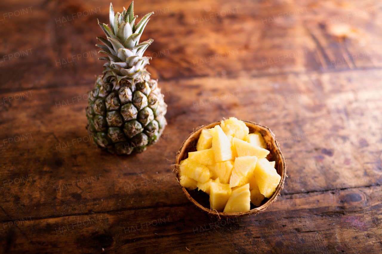 Fresh ripe pineapple, whole and chopped, laid on a table. Studio shot on old wooden background.