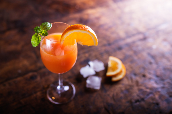 Orange juice in glass with mint and fresh fruit. Studio shot on wooden background.