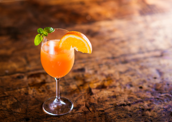 Orange juice in glass with mint and fresh fruit. Studio shot on old wooden table background. Empty copy space