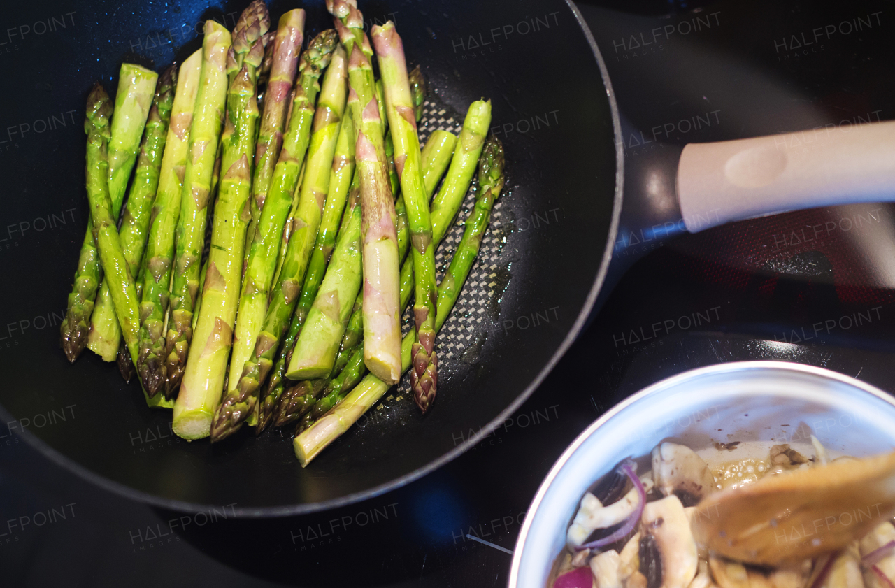 Man preparing creamy mushroom sauce and green asparagus