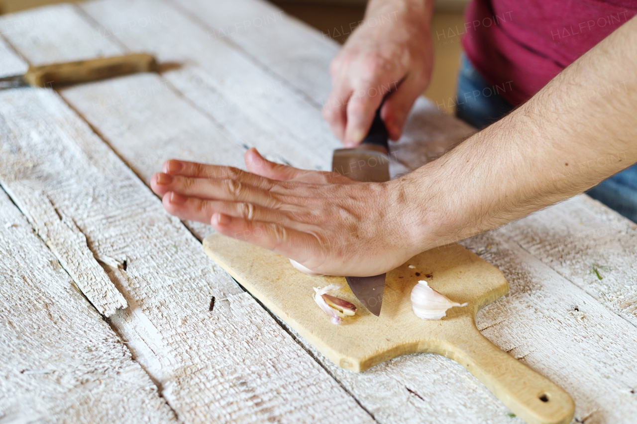 Unrecognizable man in the kitchen peeling garlic