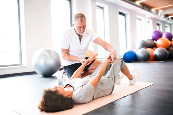 Senior physiotherapist working with an old female patient.