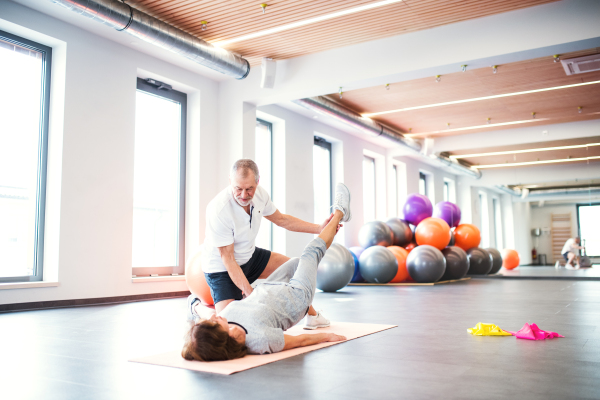 Senior physiotherapist working with an old female patient.