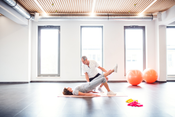 Senior physiotherapist working with an old female patient.