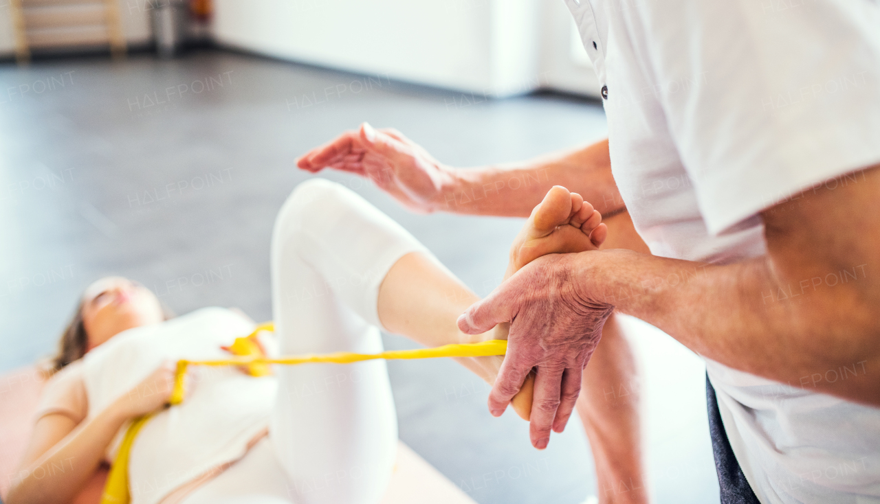 Unrecognizable senior physiotherapist working with a young female patient.