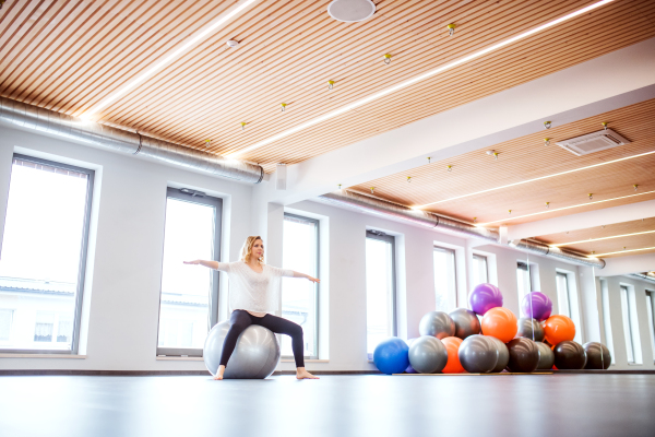 Young beautiful woman doing exercise with a fitball in a gym.