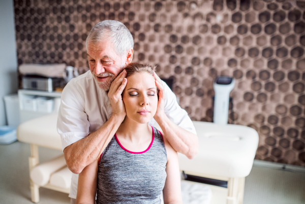 Senior male physiotherapist working with a young female patient.